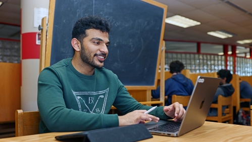 A student wearing a blue sweater types on a laptop in the Learning Centers
