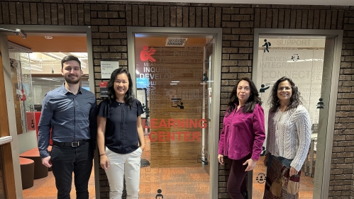 Four academic coaches stand outside the glass doors of the Learning Centers