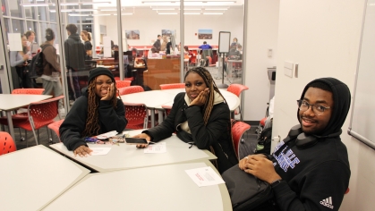 Three students sit around a conference table in a Learning Centers study space