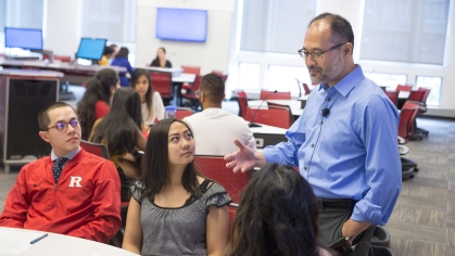 An economics instructor speaks with students in class