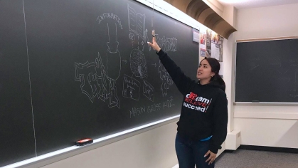 A student writes on a chalkboard during an education workshop