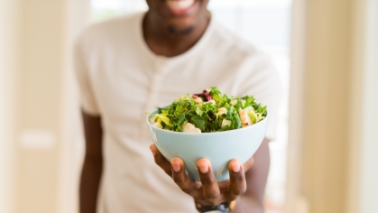 A student wearing a white t-shirt holds a salad