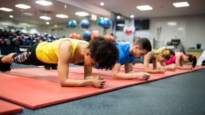 People plank while working out in a gym on red mats