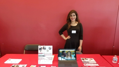 A learning center employee stands behind an information table at an event. 