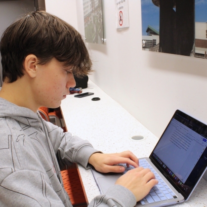 A student wearing a gray hoodie works at a computer in the Learning Centers