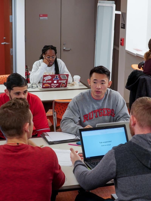 A group of students in a study group work on their laptops around a table in the Learning Center
