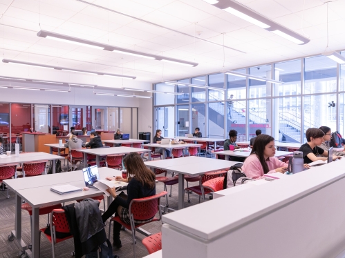 Students sitting at tables in a brightly lit Learning Center space