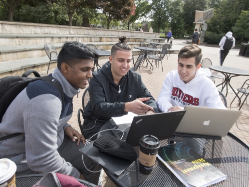 Three students studying at an outdoor table on Livingston campus in the fall