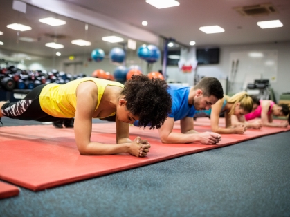 People plank while working out in a gym on red mats